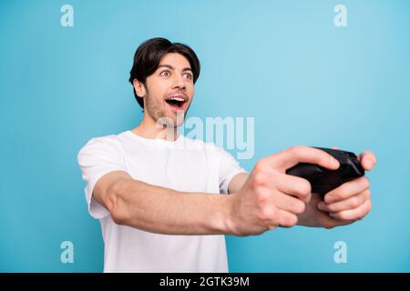 Portrait von attraktiven erstaunt fröhlichen Kerl spielen Videospiel Spaß isoliert über lebendige blaue Farbe Hintergrund Stockfoto