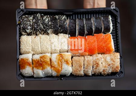 Sushi und Brötchen zu Hause zubereiten. Sushi mit Meeresfrüchten, Salat und weißem Reis. Essen für Familie und Freunde. Eine Reihe verschiedener Brötchen und Sushi auf einem Tablett Stockfoto