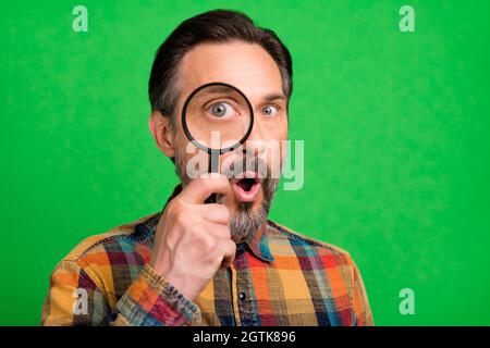 Portrait von attraktiven staunenden Mann halten Blick durch Glas finden Informationen isoliert über helle grüne Farbe Hintergrund Stockfoto