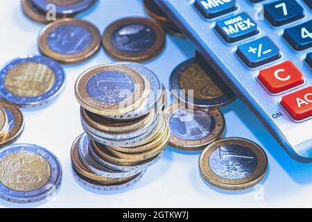 Stapel von einer und zwei Euro-Münzen neben Einem Rechner Stockfoto