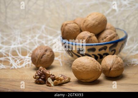 Walnusskerne und ganze Walnüsse liegen auf einem Holztisch. Stockfoto