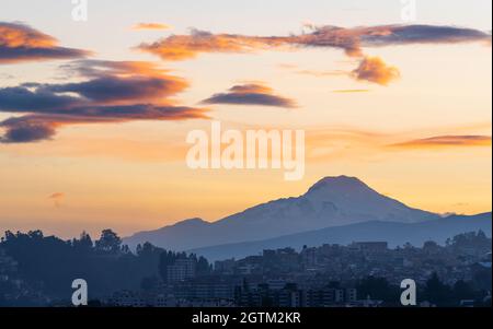 Skyline von Quito bei Sonnenaufgang mit Silhouette des Cayambe-Vulkans, Quito, Ecuador. Stockfoto