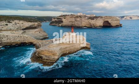 Luftaufnahme des Leuchtturms von La Madonetta in Bonifacio, an der Südspitze der Insel Korsika in Frankreich - Wellen, die auf Kalksteinfelsen krachen Stockfoto