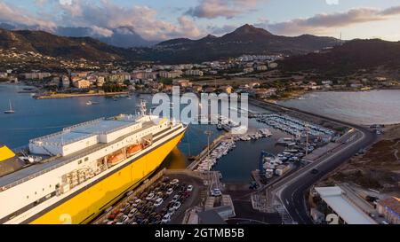 Luftaufnahme des Leuchtturms auf der Insel Pietra mit einer gelben Fähre im Hafen von Île Rousse im Hintergrund, Oberes Korsika, Frankreich - Bild Stockfoto