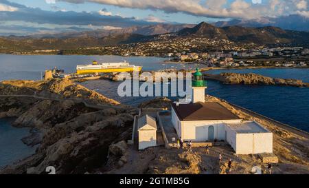 Luftaufnahme des Leuchtturms auf der Insel Pietra mit einer gelben Fähre im Hafen von Île Rousse im Hintergrund, Oberes Korsika, Frankreich - Bild Stockfoto