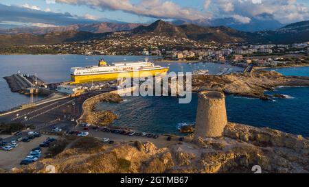 Luftaufnahme des Leuchtturms auf der Insel Pietra mit einer gelben Fähre im Hafen von Île Rousse im Hintergrund, Oberes Korsika, Frankreich - Bild Stockfoto