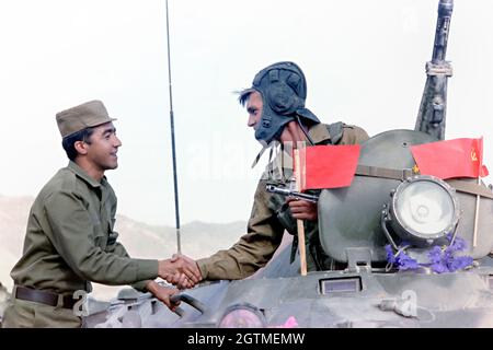 KABUL, AFGHANISTAN. Mai 1988. Ein sowjetischer russischer Soldat, rechts, schüttelt einem afghanischen Kollegen die Hände, als er mit seinem Konvoi zu Beginn des Abzugs der sowjetischen Streitkräfte aus dem Land am 16. Mai 1988 in Kabul, Afghanistan, abreist. Stockfoto