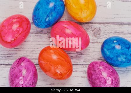 Ansicht von oben auf farbigen Ostereiern auf Einer weißen Holzoberfläche, Makro-Farbfoto mit Kopierbereich Stockfoto