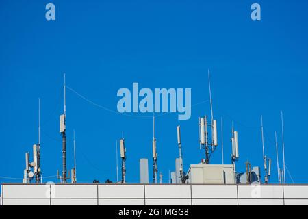 Die Tafelantenne der GSM DCS UMTS LTE-Bänder und der Funkeinheit sind als Teil der Kommunikationsausrüstung der Basisstation auf dem Dach Eines Gebäudes installiert Stockfoto