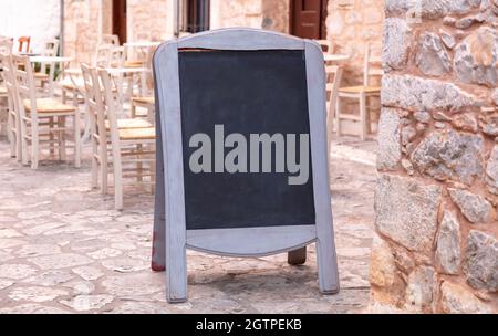 Menuboard. Kreidetafel blank mit Holzrahmen im Freien auf einem gepflasterten Gehweg aus Stein. Heute Menü Vorlage, traditionelle Dorf Taverne in Griechenland, Stockfoto