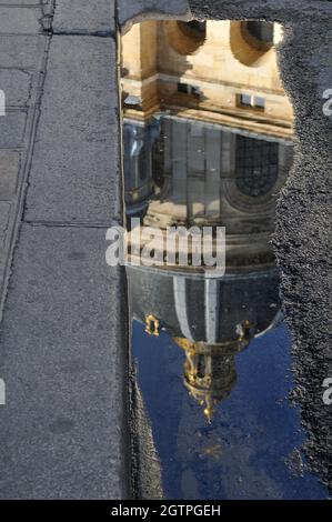 Die Kuppel des Institut de France spiegelt sich in einer Pfütze auf einer Pariser Straße wider. Das Gebäude beherbergte ursprünglich die Collège des Quatre-Nations. Stockfoto