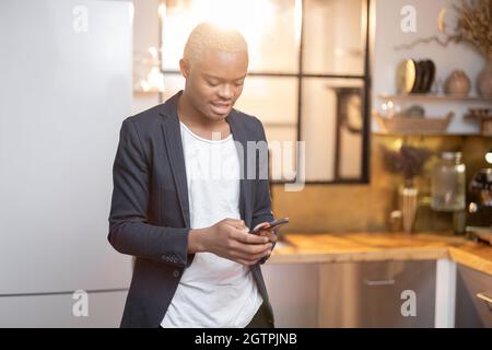 Schwarzer Mann, der etwas auf dem Smartphone beobachtet Stockfoto