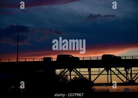 Fahrzeuge, die bei Sonnenuntergang über der Mautstraße auf der Mackinac Bridge, einer der längsten Brücken der Welt, über die Straße von Mackinac, fahren, Mackinaw City, MI, USA Stockfoto