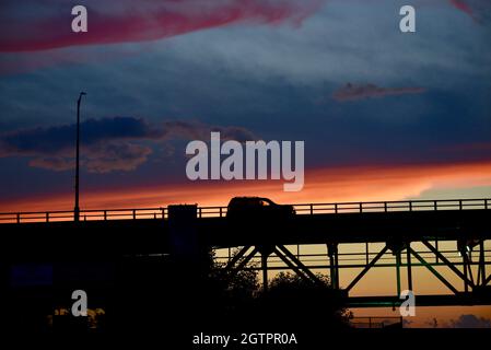 Fahrzeuge, die bei Sonnenuntergang über der Mautstraße auf der Mackinac Bridge, einer der längsten Brücken der Welt, über die Straße von Mackinac, fahren, Mackinaw City, MI, USA Stockfoto