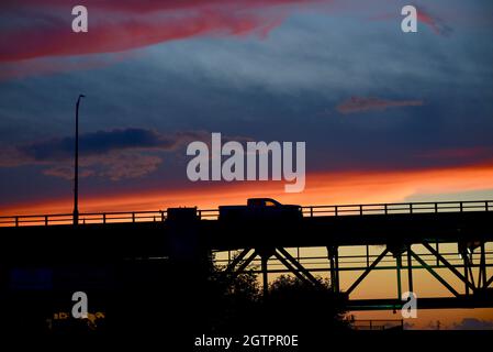 Fahrzeuge, die bei Sonnenuntergang über der Mautstraße auf der Mackinac Bridge, einer der längsten Brücken der Welt, über die Straße von Mackinac, fahren, Mackinaw City, MI, USA Stockfoto