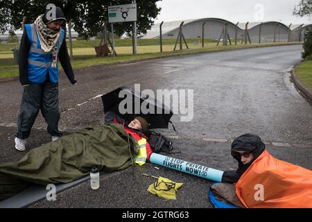 Farnborough, Großbritannien. Oktober 2021. Die Bilder der Klimaaktivisten der Extinction Rebellion werden mit einem Armrohr zusammengeschlossen dargestellt, um einen Eingang zum Flughafen Farnborough zu blockieren. Aktivisten blockierten drei Zugänge zum privaten Flughafen, um erhöhte Kohlendioxidwerte hervorzuheben, die von superreichen Passagieren mit privaten Jets und "Greenwashing" vom Flughafen produziert werden, indem sie einen Wechsel zu nachhaltigem Flugkraftstoff (SAF) ankündigten. Kredit: Mark Kerrison/Alamy Live Nachrichten Stockfoto