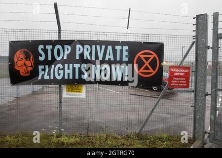 Farnborough, Großbritannien. Oktober 2021. Vor dem Eingang zum Flughafen Farnborough wird ein Banner von Klimaaktivisten der Extinction Rebellion gezeigt. Aktivisten blockierten drei Zugänge zum privaten Flughafen, um erhöhte Kohlendioxidwerte hervorzuheben, die von superreichen Passagieren mit privaten Jets und "Greenwashing" vom Flughafen produziert werden, indem sie einen Wechsel zu nachhaltigem Flugkraftstoff (SAF) ankündigten. Kredit: Mark Kerrison/Alamy Live Nachrichten Stockfoto
