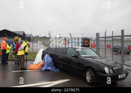 Farnborough, Großbritannien. Oktober 2021. Ein Klimaaktivist der Extinction Rebellion sitzt in einer Stretch-Limousine eingesperrt und blockiert den Eingang zum Flughafen Farnborough. Aktivisten blockierten drei Zugänge zum privaten Flughafen, um erhöhte Kohlendioxidwerte hervorzuheben, die von superreichen Passagieren mit privaten Jets und "Greenwashing" vom Flughafen produziert werden, indem sie einen Wechsel zu nachhaltigem Flugkraftstoff (SAF) ankündigten. Kredit: Mark Kerrison/Alamy Live Nachrichten Stockfoto