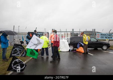 Farnborough, Großbritannien. Oktober 2021. Ein Klimaaktivist der Extinction Rebellion sitzt in einer Stretch-Limousine eingesperrt und blockiert den Eingang zum Flughafen Farnborough. Aktivisten blockierten drei Zugänge zum privaten Flughafen, um erhöhte Kohlendioxidwerte hervorzuheben, die von superreichen Passagieren mit privaten Jets und "Greenwashing" vom Flughafen produziert werden, indem sie einen Wechsel zu nachhaltigem Flugkraftstoff (SAF) ankündigten. Kredit: Mark Kerrison/Alamy Live Nachrichten Stockfoto