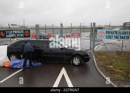 Farnborough, Großbritannien. Oktober 2021. Ein Klimaaktivist der Extinction Rebellion liegt in einer Stretch-Limousine, die den Eingang zum Flughafen Farnborough blockiert. Aktivisten blockierten drei Zugänge zum privaten Flughafen, um erhöhte Kohlendioxidwerte hervorzuheben, die von superreichen Passagieren mit privaten Jets und "Greenwashing" vom Flughafen produziert werden, indem sie einen Wechsel zu nachhaltigem Flugkraftstoff (SAF) ankündigten. Kredit: Mark Kerrison/Alamy Live Nachrichten Stockfoto