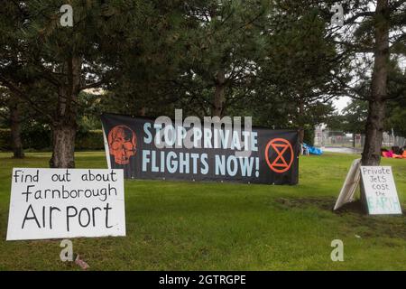 Farnborough, Großbritannien. Oktober 2021. Vor dem Eingang zum Flughafen Farnborough sind ein Banner und Schilder von Extinction Rebellion-Klimaaktivisten ausgestellt. Aktivisten blockierten drei Zugänge zum privaten Flughafen, um erhöhte Kohlendioxidwerte hervorzuheben, die von superreichen Passagieren mit privaten Jets und "Greenwashing" vom Flughafen produziert werden, indem sie einen Wechsel zu nachhaltigem Flugkraftstoff (SAF) ankündigten. Kredit: Mark Kerrison/Alamy Live Nachrichten Stockfoto