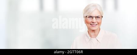 Porträt einer Frau mit Brille, eines Rentners, einer älteren Person, die vor verschwommenem Hintergrund lächelt Stockfoto