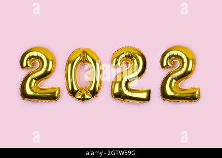 2022 Banner mit goldenen Folienballons auf rosa Hintergrund. Zahlen 2022 Goldballons auf rosa Wand. Neujahrskarte. Frohes neues Jahr Feier Partei Stockfoto