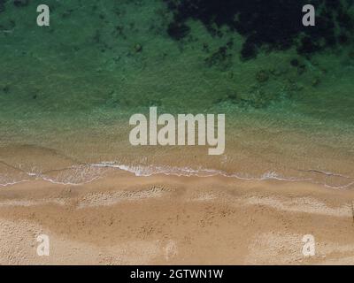 Schöner abgelegener Strand mit kristallklarem azurblauem Wasser, Luftbild. Unberührte Natur und versteckter Sandstrand mit Möwen. Bewegungsunschärfe bei kleinen Wellen Stockfoto