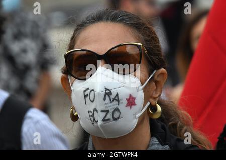 Lissabon, Portugal. Oktober 2021. Ein Aktivist trägt während einer Kundgebung auf dem Rossio-Platz eine Schutzmaske mit Inschriften.die Kampagne Fora Bolsonaro (Out with Bolsonaro), Die in Lissabon verschiedene Organisationen, Parteien, Gewerkschaften und Bewegungen für Demokratie und die Rechte des Volkes zusammenbringt, veranstaltete eine Kundgebung zur Ablehnung der Politik des brasilianischen Präsidenten Jair Bolsonaro und forderte seinen Rücktritt als Staatsoberhaupt. (Foto von Jorge Castellanos/SOPA Images/Sipa USA) Quelle: SIPA USA/Alamy Live News Stockfoto