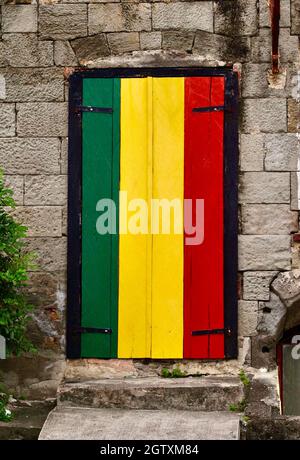 Die Farben der Rastafari/Reggae-Flagge an der Tür und den Fensterläden einer Bar in Roseau, Dominica. Stockfoto