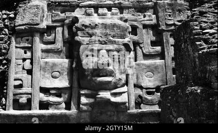 Monochrome Nahaufnahme der linken Maske an der Fassade des Maskentempels in Lamanai. Stockfoto