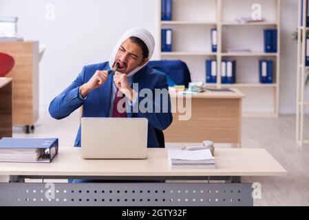 Junger Geschäftsmann, der am Arbeitsplatz an Zahnschmerzen leidet Stockfoto