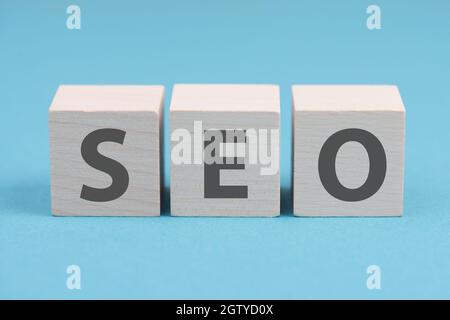 Das Wort SEO steht auf Holzwürfeln, blauer Hintergrund Stockfoto