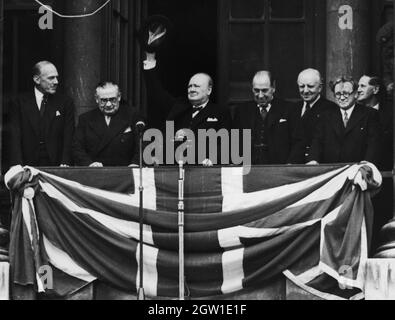 Der britische Premierminister Winston Churchill spricht am VE-Tag, 8. Mai 1945, vom Balkon des Gesundheitsministeriums in Whitehall zu den Menschenmassen. Von links nach rechts Ernest Bevin, Churchill, Sir John Anderson, Lord Woolton und Herbert Morrison Stockfoto