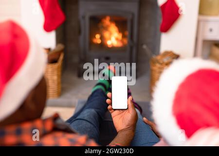 Rückansicht eines afroamerikanischen Seniorenpaares, das zur weihnachtszeit ein Smartphone mit Kopierplatz verwendet Stockfoto