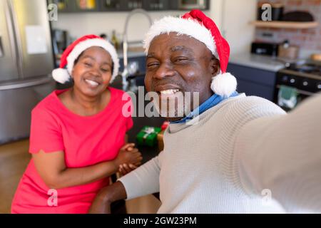 Glückliches afroamerikanisches Seniorenpaar, das zur weihnachtszeit Selfie in der Küche macht Stockfoto