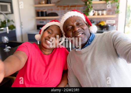 Glückliches afroamerikanisches Seniorenpaar, das zur weihnachtszeit Selfie in der Küche macht Stockfoto