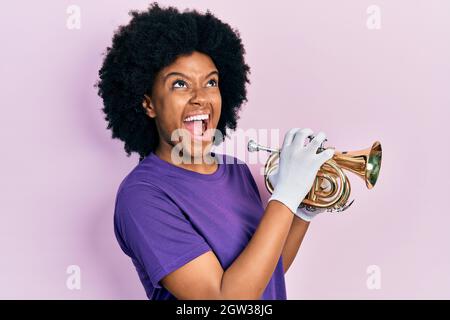 Junge afroamerikanische Frau, die Trompete spielt, wütend und wütend schreiend, frustriert und wütend, schreiend, mit Wut aufschauend. Stockfoto