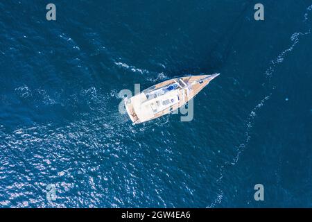 Sommerurlaub auf dem Wasser. Luftaufnahme einer schönen weißen Segelyacht mit einem farbigen Segel. Stockfoto