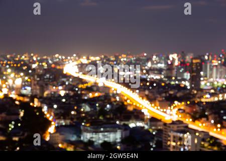 Verwischen Sie Bokeh-Hintergrund mit Stadtbild in der Dämmerung, verschwommener Fokus am Abend mit Innenstadt, Landschaft, beleuchtet und Licht. Stockfoto