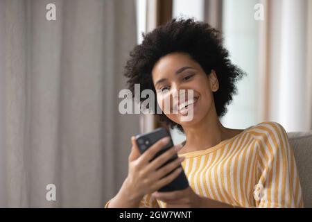 Glückliche junge afroamerikanische Frau mit Handy. Stockfoto