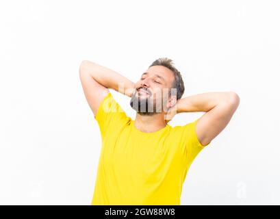 Ein positiver Mann mit gelbem Hemdportrait an der Wand Stockfoto