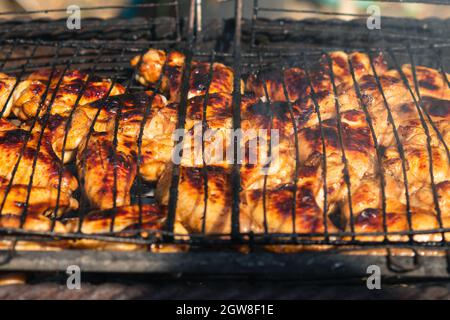 Goldene Hähnchenflügel rösten auf einem Grill über Holzkohle. Selektiver Fokus. Das Konzept des Kochens im Hinterhof Stockfoto