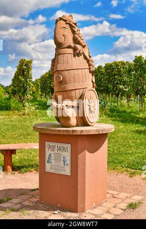 Wiesloch, Deutschland - August 2021: Lustige Skulptur des weingottes namens 'Speedy Bacchus' mit verschwommenem Weinberg im Hintergrund Stockfoto