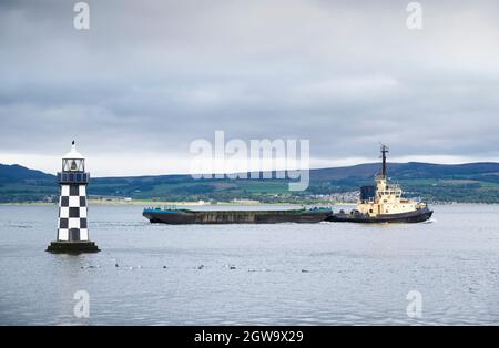 Schlepper transportieren schwimmende Speichercontainer Plattform und Leuchtturm Stockfoto