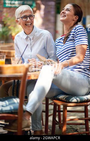 Vertikales Bild von jungen erwachsenen Frauen, die zusammen mit älteren Frauen lachen, die ein Buch halten. Stockfoto