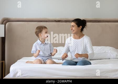 Fröhliche zwei Generationen gemischte Rasse Familie spielt zusammen im Schlafzimmer. Stockfoto