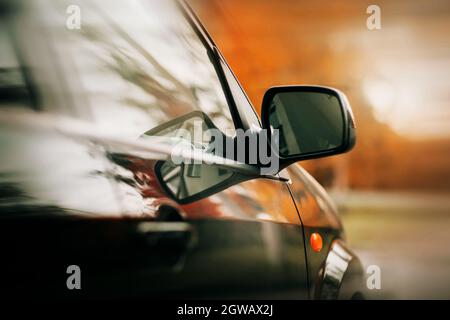 Ein schwarz poliertes neues Auto fährt an einem herbstlichen hellen Tag schnell auf der Straße. Die Reise ist im Oktober. Geschwindigkeit. Stockfoto