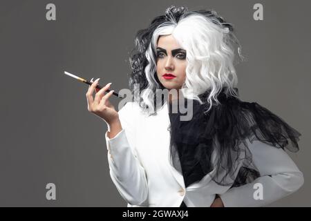 Eine tödliche Schönheit in einem gewagten Modebild mit schwarzen und weißen Haaren. Ein rebellisches stylisches Bild für Halloween. Eine junge Frau in einem schwarz-weißen Outfi Stockfoto