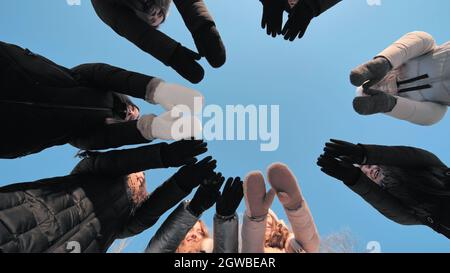 Freunde an einem Wintertag verbinden sich mit Fäustlingen im Kreis. Stockfoto